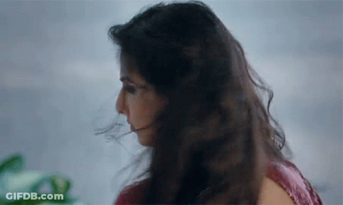 A Close Up Of A Woman 'S Face With Her Hair Blowing In The Wind GIF