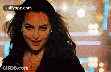 A Close Up Of A Woman 'S Face With Her Hair Blowing In The Wind And Smiling . GIF