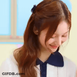 A Close Up Of A Woman 'S Face With Her Hair In A Half Up Half Down Ponytail . GIF