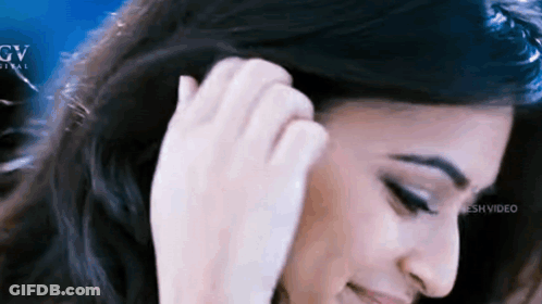 A Close Up Of A Woman 'S Face With Her Hand In Her Hair . GIF