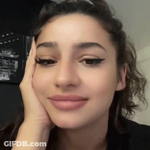 A Close Up Of A Woman 'S Face With Her Hand On Her Cheek GIF