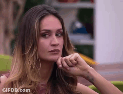 A Close Up Of A Woman 'S Face With Her Hand On Her Chin Looking At The Camera . GIF