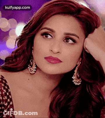 A Close Up Of A Woman 'S Face With Her Hand On Her Face And Earrings . GIF