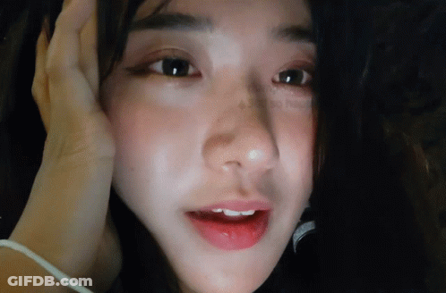 A Close Up Of A Woman 'S Face With Her Hand On Her Forehead GIF