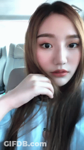 A Close Up Of A Woman 'S Face With Her Hand On Her Hair GIF