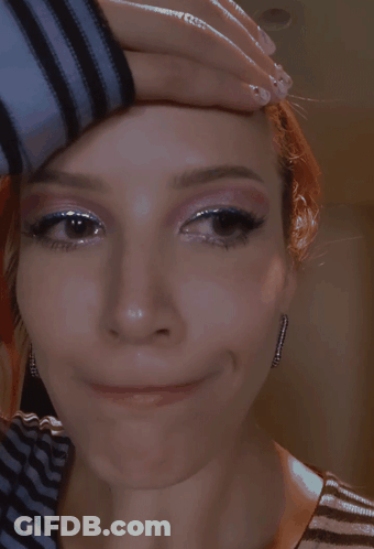 A Close Up Of A Woman 'S Face With Her Hand On Her Head GIF