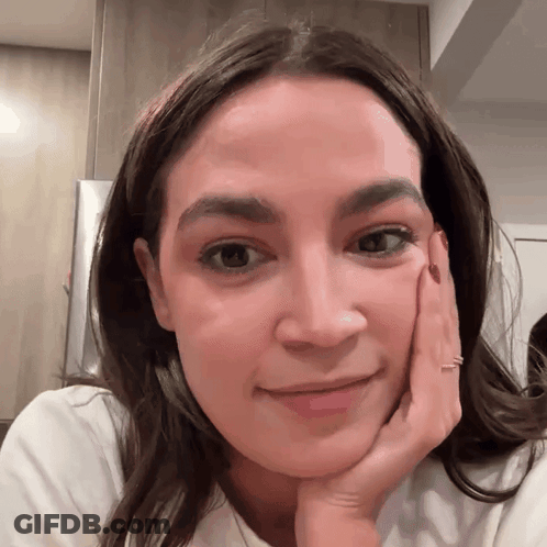 A Close Up Of A Woman 'S Face With Her Hand Resting On Her Chin GIF