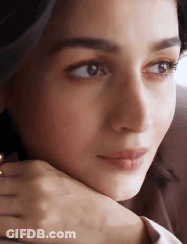 A Close Up Of A Woman 'S Face With Her Hand Under Her Chin GIF