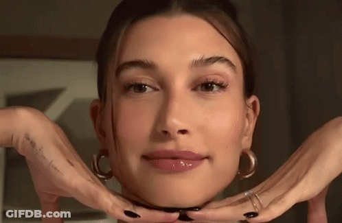 A Close Up Of A Woman 'S Face With Her Hands Making A Face . GIF