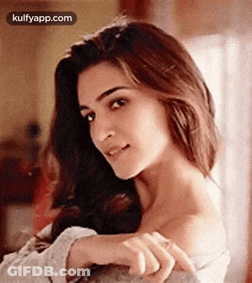 A Close Up Of A Woman 'S Face With Her Hands On Her Shoulder And Looking At The Camera . GIF