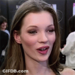 A Close Up Of A Woman 'S Face With Her Mouth Open And A Crowd Behind Her . GIF