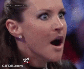 A Close Up Of A Woman 'S Face With Her Mouth Open And A Wrestling Logo On Her Chest . GIF