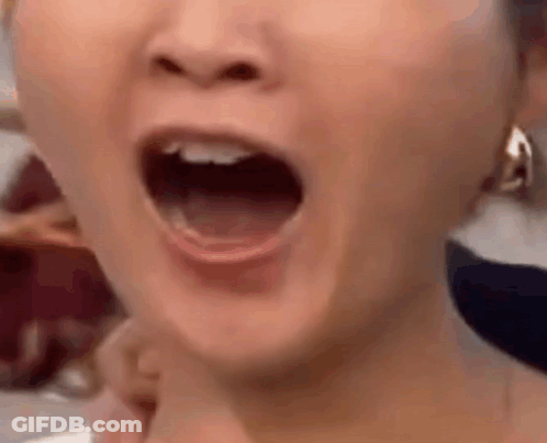 A Close Up Of A Woman 'S Face With Her Mouth Open And Earrings . GIF
