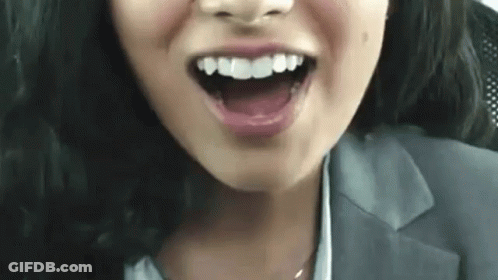 A Close Up Of A Woman 'S Face With Her Mouth Open And Her Teeth Showing . GIF