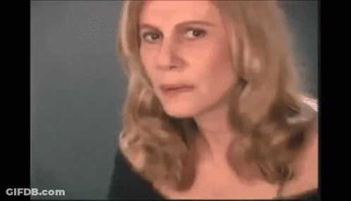 A Close Up Of A Woman 'S Face With Long Blonde Hair And A Black Dress . GIF
