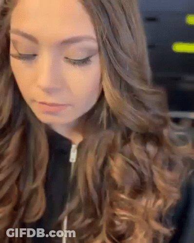 A Close Up Of A Woman 'S Face With Long Brown Hair And A Black Jacket . GIF