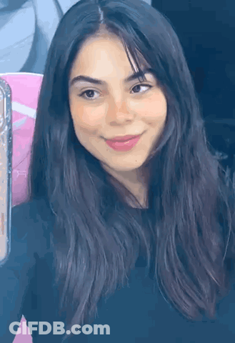 A Close Up Of A Woman 'S Face With Long Dark Hair And A Smile . GIF