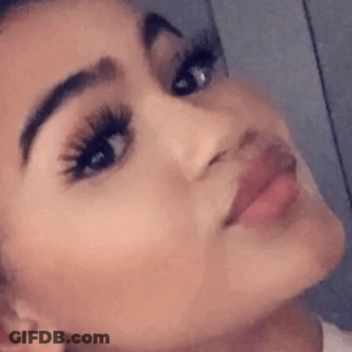A Close Up Of A Woman 'S Face With Long Eyelashes And A Slight Smile . GIF