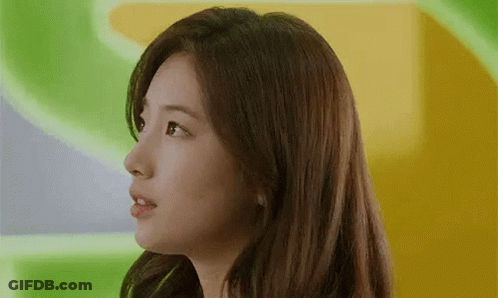 A Close Up Of A Woman 'S Face With Long Hair Against A Green And Yellow Background . GIF