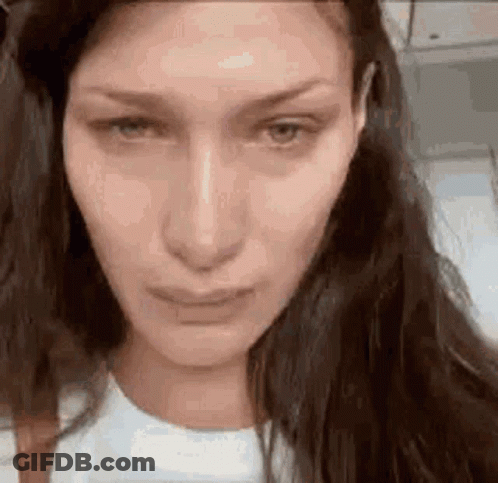 A Close Up Of A Woman 'S Face With Long Hair And A Sad Look On Her Face . GIF