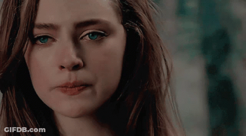 A Close Up Of A Woman 'S Face With Long Hair And Blue Eyes GIF