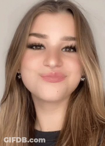 A Close Up Of A Woman 'S Face With Long Hair And Earrings GIF
