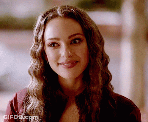 A Close Up Of A Woman 'S Face With Long Wavy Hair GIF