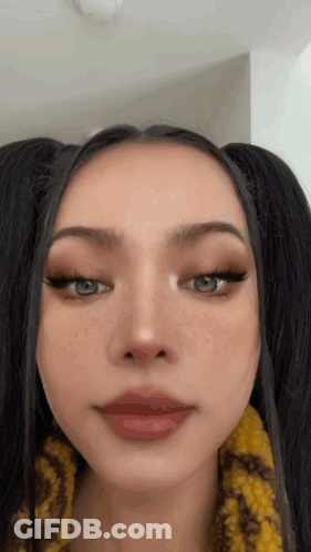 A Close Up Of A Woman 'S Face With Pigtails And Red Lips . GIF