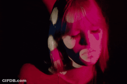 A Close Up Of A Woman 'S Face With Pink Flowers Projected On Her Face GIF