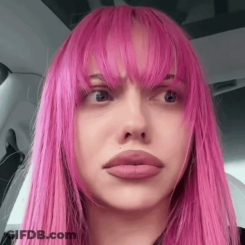 A Close Up Of A Woman 'S Face With Pink Hair And Bangs GIF