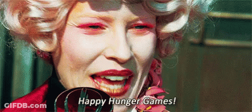 A Close Up Of A Woman 'S Face With Pink Makeup And The Words `` Happy Hunger Games ! '' GIF