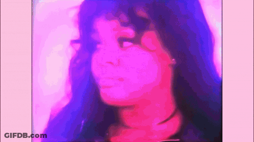 A Close Up Of A Woman 'S Face With Purple And Pink Lighting Behind Her . GIF