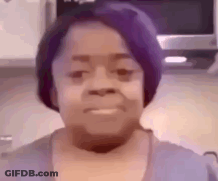 A Close Up Of A Woman 'S Face With Purple Hair . GIF
