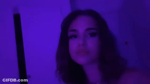 A Close Up Of A Woman 'S Face With Purple Lights Behind Her . GIF