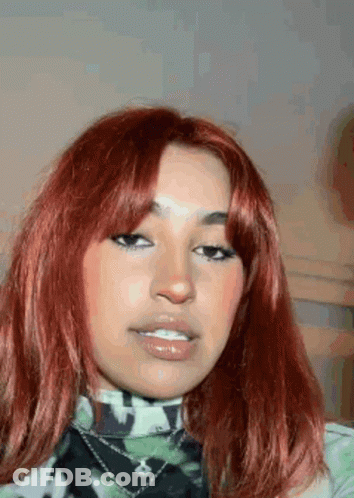 A Close Up Of A Woman 'S Face With Red Hair And A Camouflage Shirt . GIF
