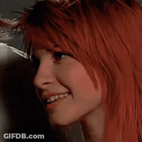 A Close Up Of A Woman 'S Face With Red Hair And A Smile . GIF