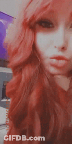 A Close Up Of A Woman 'S Face With Red Hair Making A Funny Face . GIF