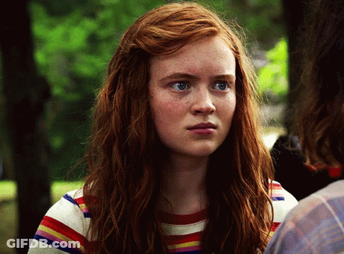 A Close Up Of A Woman 'S Face With Red Hair Wearing A Striped Shirt GIF