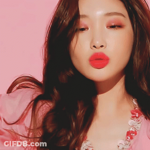 A Close Up Of A Woman 'S Face With Red Lips And A Pink Background GIF