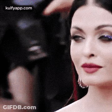 A Close Up Of A Woman 'S Face With Red Lipstick And Blue Eye Shadow . GIF