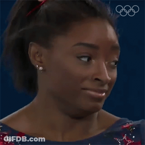 A Close Up Of A Woman 'S Face With The Olympic Rings Behind Her . GIF