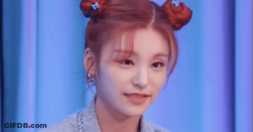 A Close Up Of A Woman 'S Face With Two Buns In Her Hair . GIF