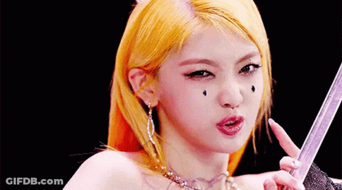 A Close Up Of A Woman 'S Face With Yellow Hair Holding A Sword . GIF