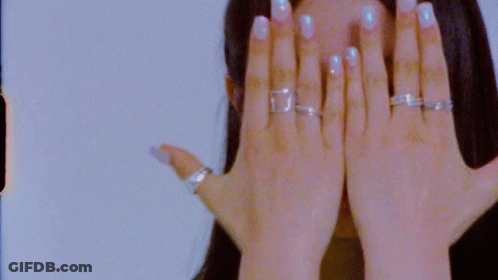 A Close Up Of A Woman 'S Hand With Rings On It Covering Her Face . GIF