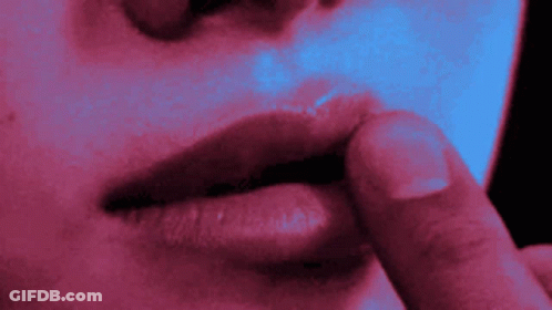A Close Up Of A Woman 'S Lips With A Finger On Her Lips GIF