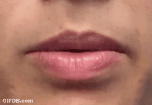 A Close Up Of A Woman 'S Lips With Pink Lipstick And Teeth . GIF