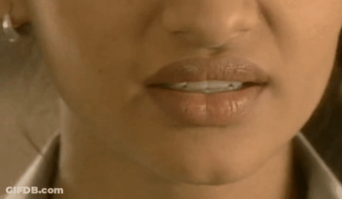 A Close Up Of A Woman 'S Mouth With Her Tongue Out And A White Shirt On . GIF