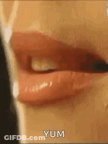 A Close Up Of A Woman 'S Mouth With Red Lipstick And The Words Yum Written On It . GIF