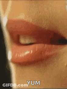 A Close Up Of A Woman 'S Mouth With Red Lipstick And The Words `` Yum '' Written On It . GIF