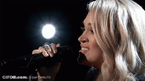 A Close Up Of A Woman Singing Into A Microphone GIF